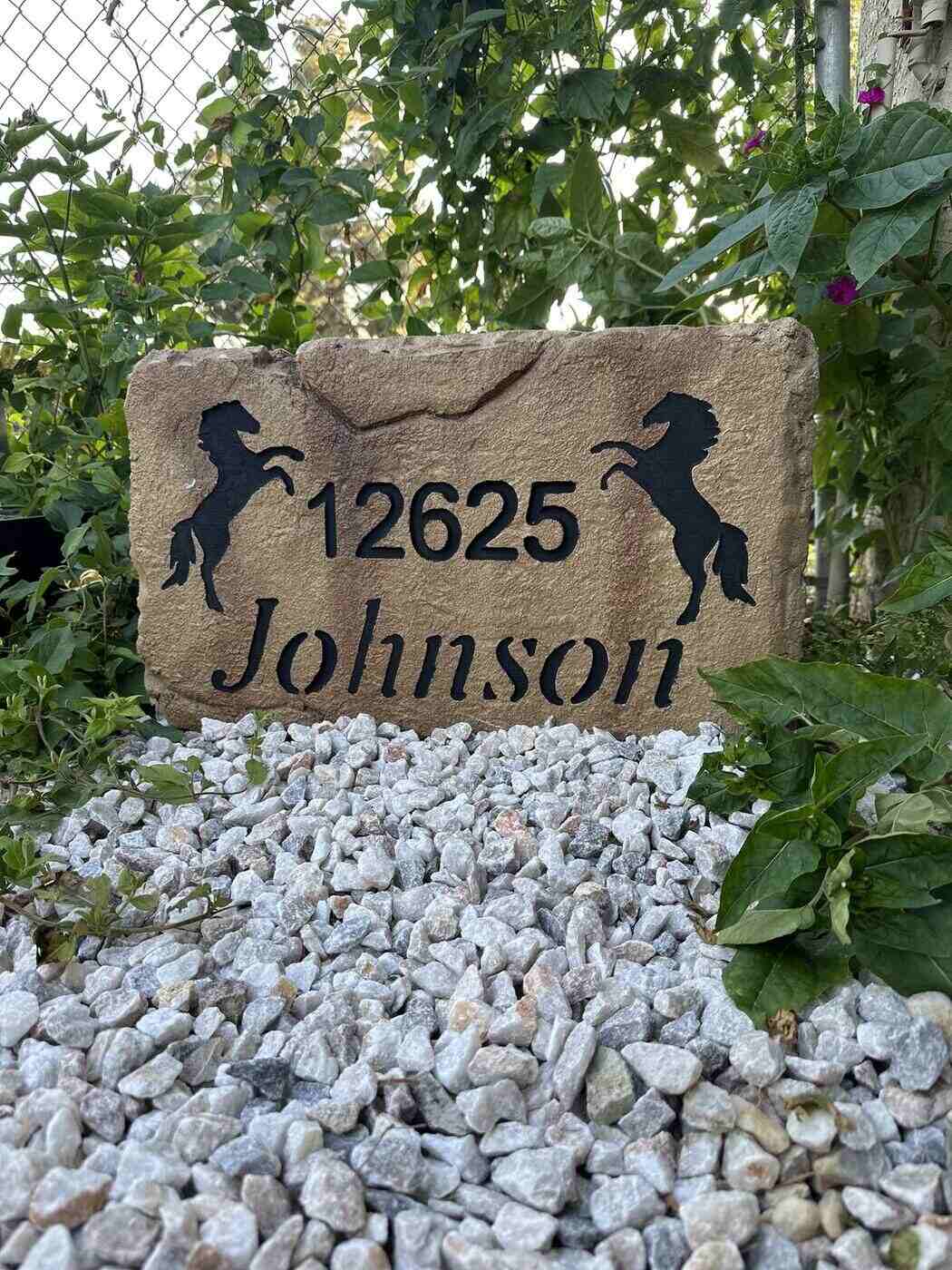 Engraved address stone with horse artwork installed in landscaping