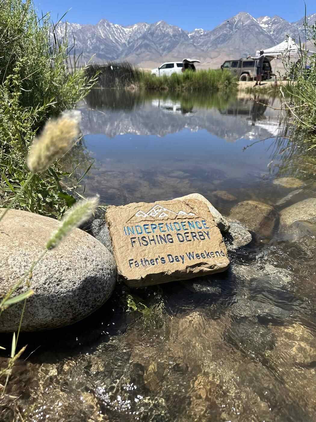 Engraved commemorative stone marker placed at a creek for a community fishing derby